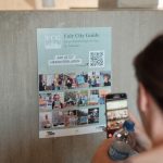 Fairy City Guide Plakat und Person, die Smartphone hält